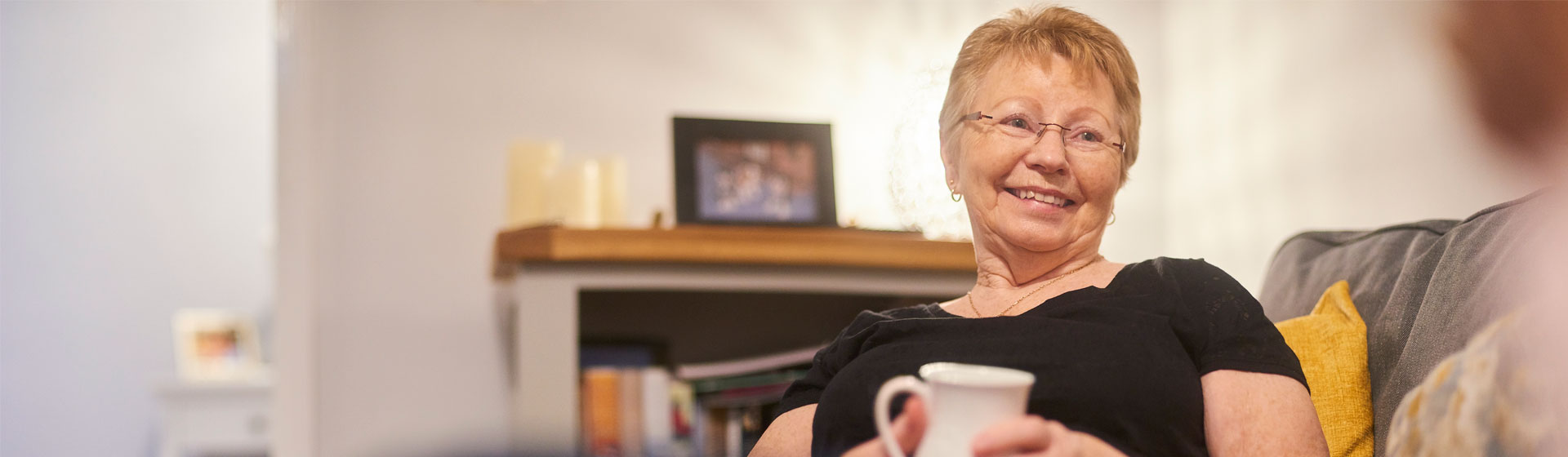 Elderly woman smiling holding a coffee mug