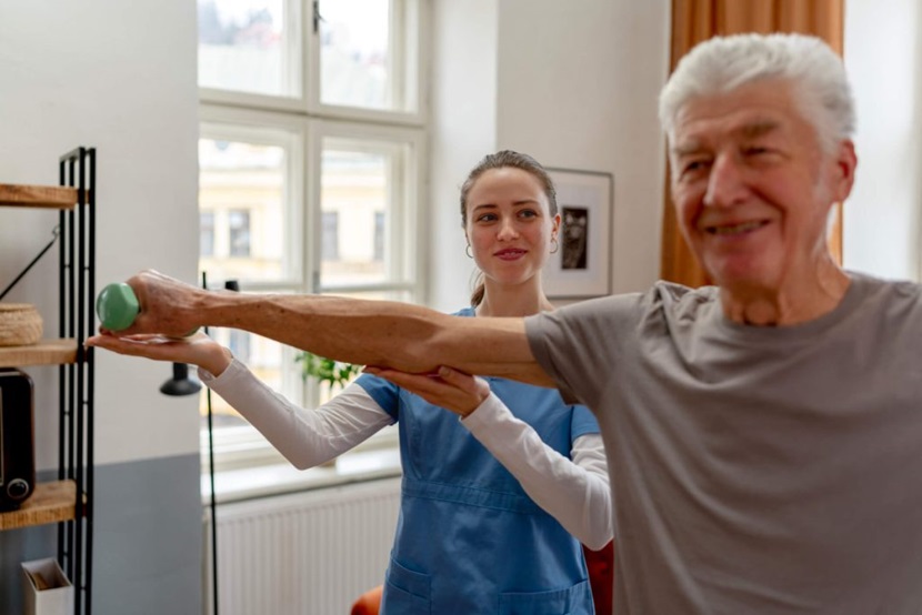 Senior receives help exercising in assisted living house