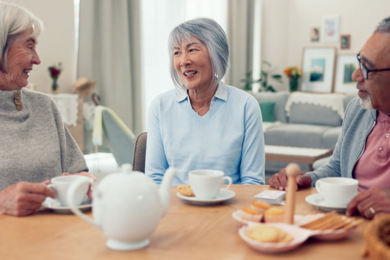 Elderly people sitting around a table having tea