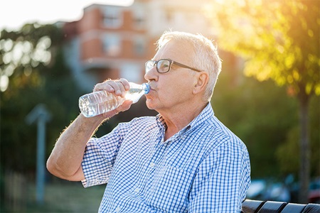 Man sitting on a bench drinking water